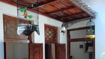 Una habitación tradicional con vigas de madera, suelo de baldosas y una cama con colcha blanca.