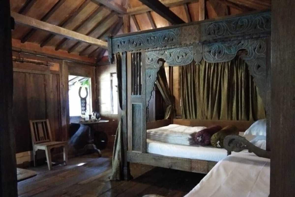 Um quarto rústico de madeira com uma cama de dossel, uma cadeira de madeira e uma mesa pequena.