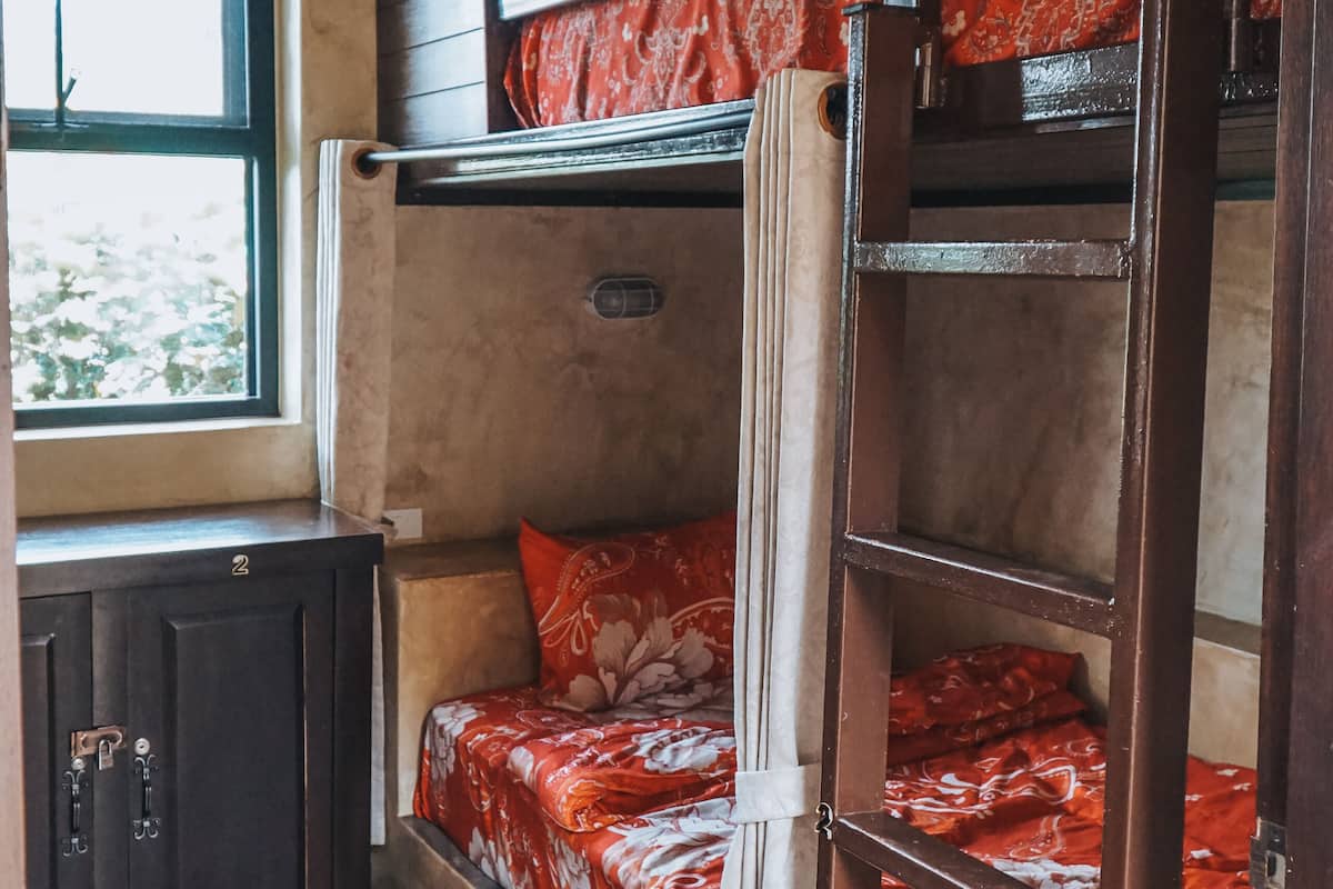 A bunk bed room with a window, a radiator, and a door.