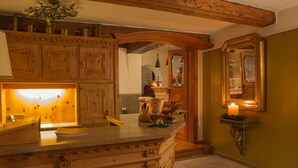 A kitchen with wooden cabinetry, a marble countertop, and a lit candle on a small table. - Chalet Brunnenhof (Sankt Anton am Arlberg)