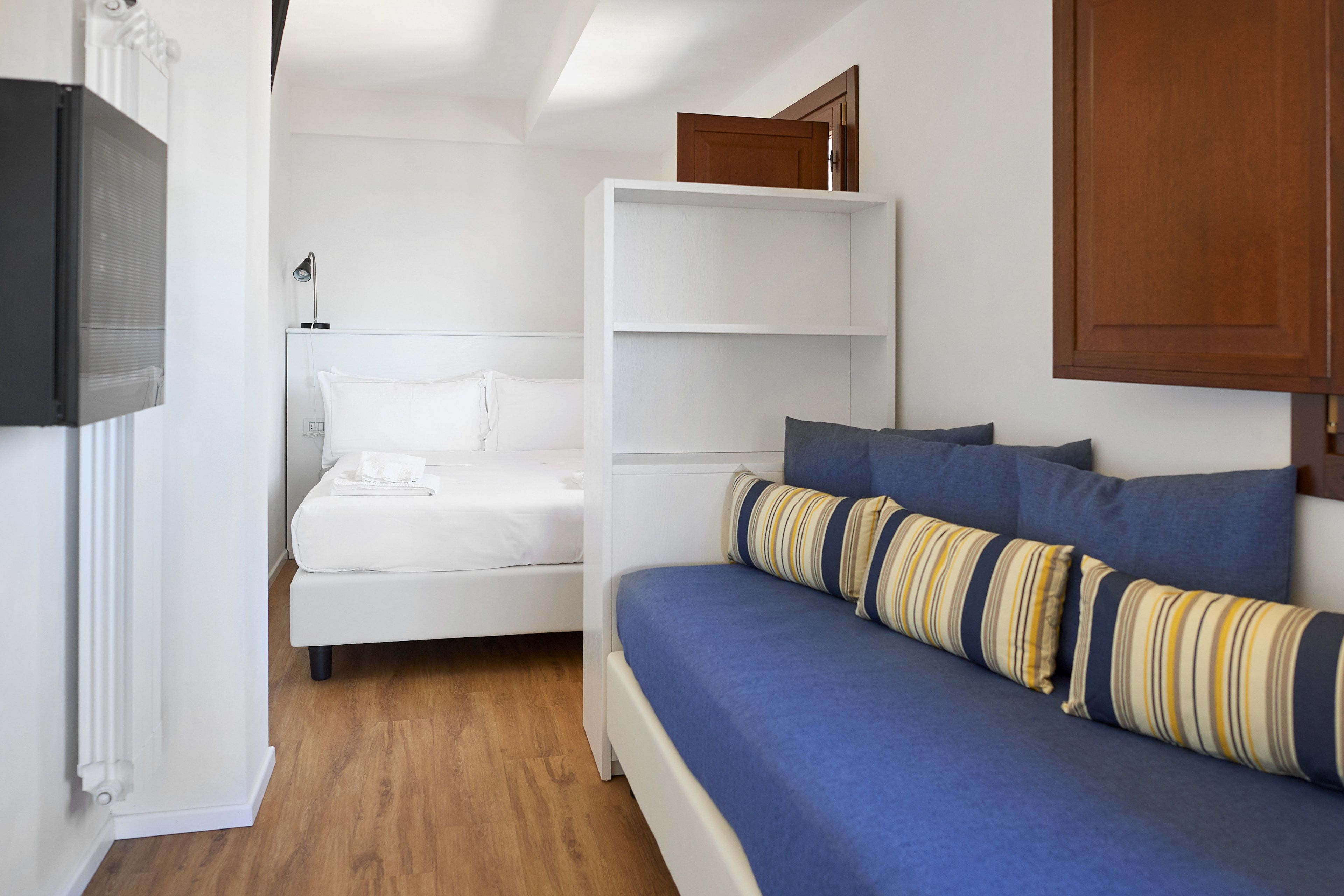Un dormitorio con cama, sofá, televisión y armario de madera.