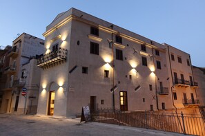 Ein mehrstöckiges Gebäude mit Balkonen und beleuchteten Fenstern, das an ein Hotel oder eine Wohnanlage erinnert.