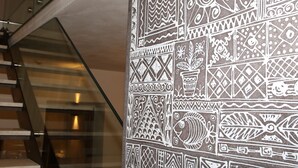 Un escalier doté d’une rampe en verre et d’un mur orné de motifs blancs complexes.