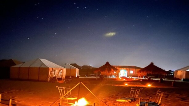 Ein Nachtcamp in der Wüste mit Zelten und Lagerfeuer.