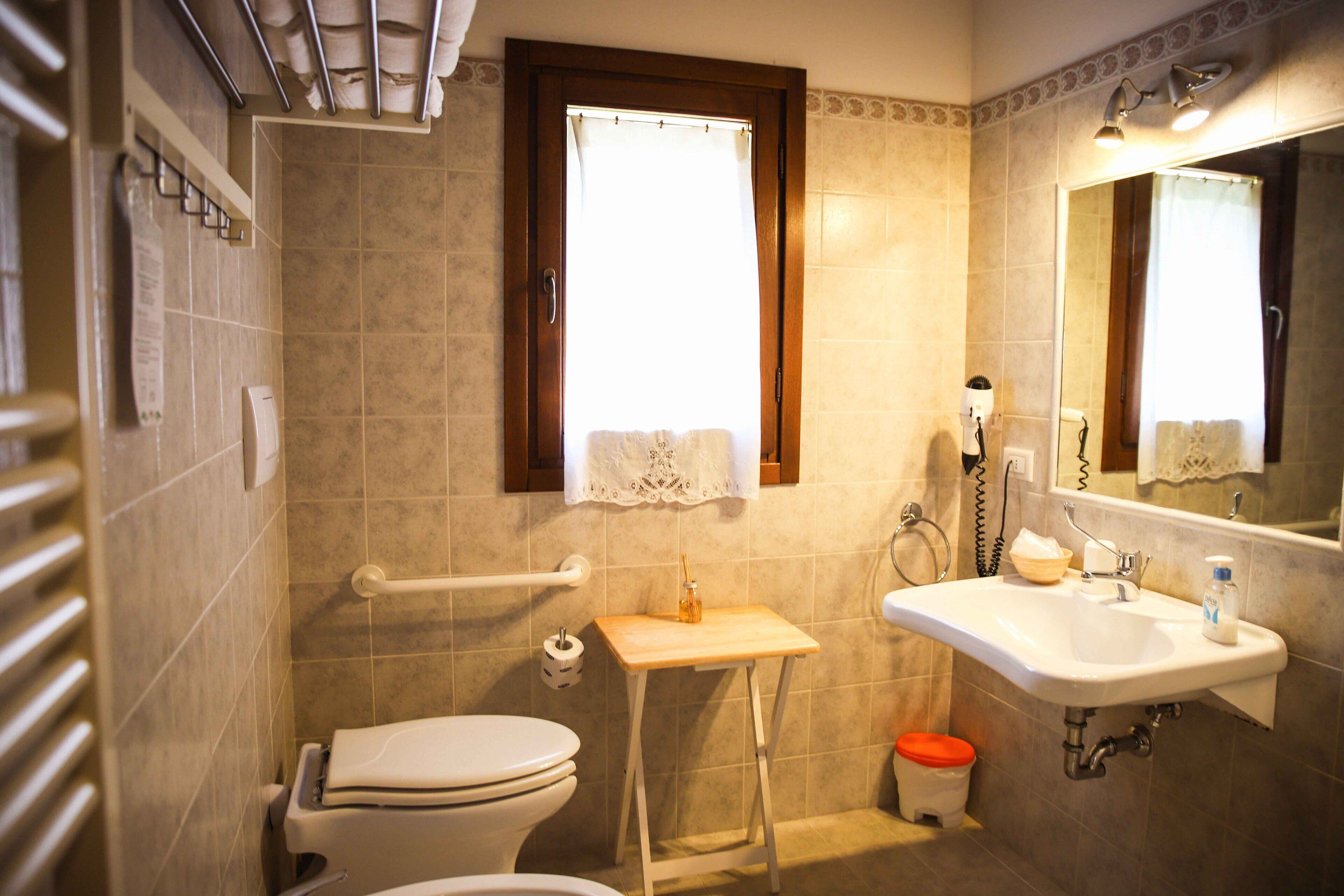 Un baño con inodoro, lavamanos, espejo y ventana.