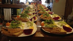 Ein langer Tisch mit mehreren Tellern Essen, darunter Brot, Gemüse und Obst.