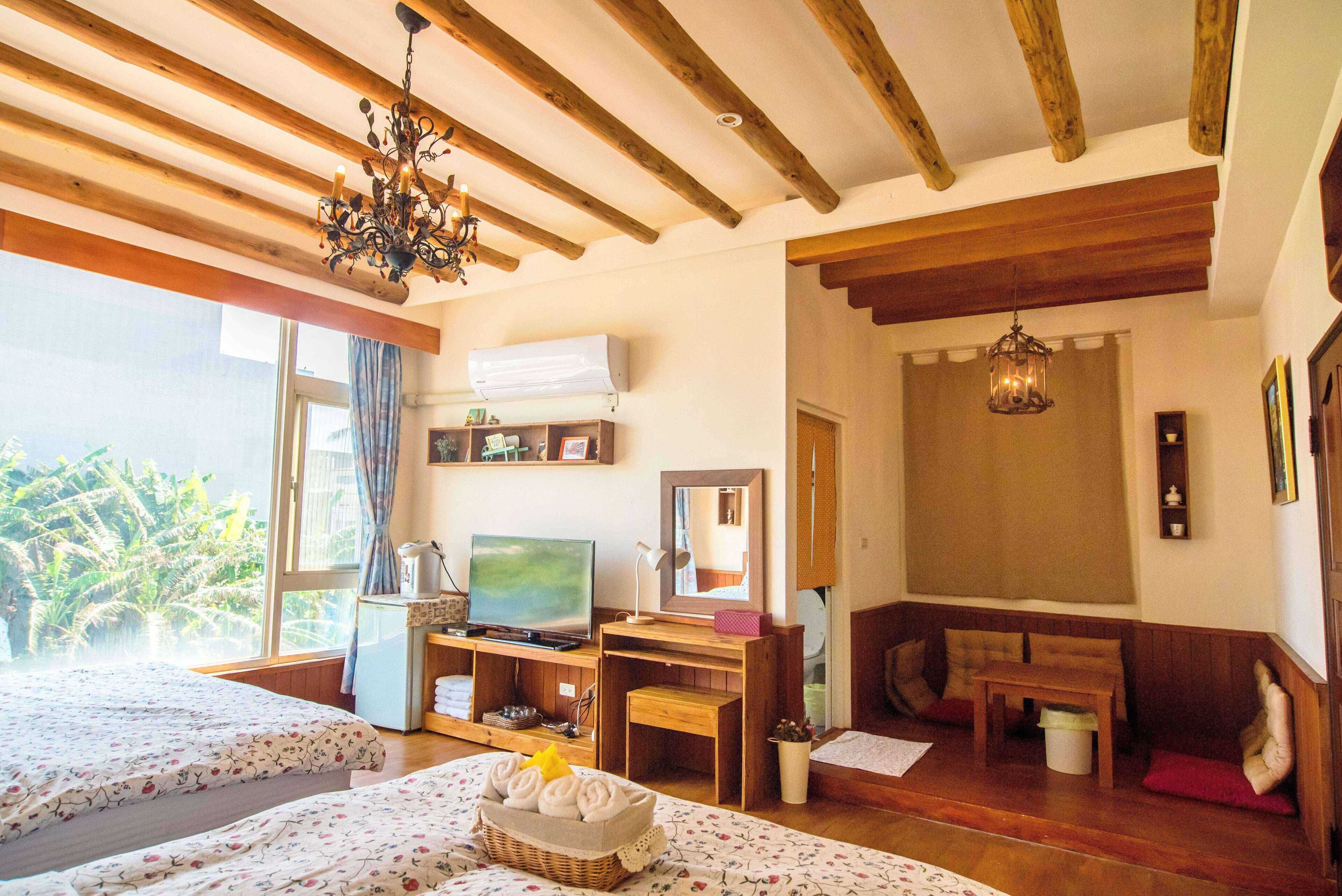 Una habitación con dos camas, televisión, escritorio y ventana con vistas a la vegetación.