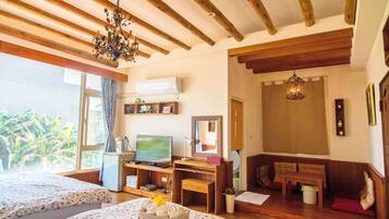 Una habitación con dos camas, televisión, escritorio y ventana con vistas a la vegetación.