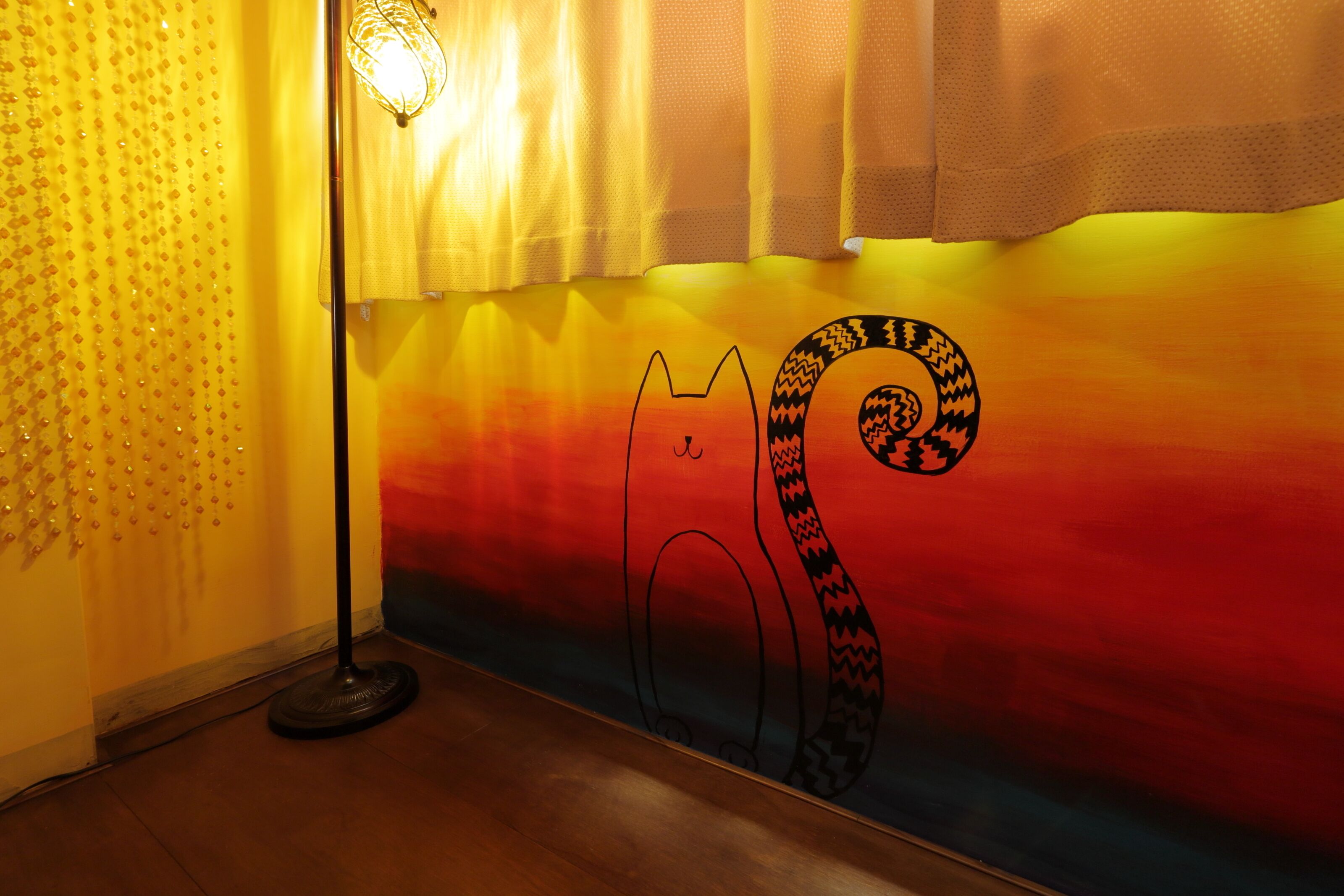 A room with a colorful gradient wall, a standing lamp, and a decorative wall panel.
