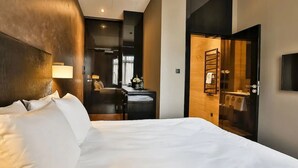A hotel room with a large bed, a desk, a chair, a lamp, and a bathroom visible through an open door. - Medusa Gdańsk (Gdansk)