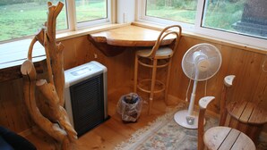 A cozy room with a wooden table, a fan, a chair, and a radiator. - Woody Life (Kamifurano)
