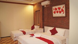 A hotel room with two beds, a brick wall, and a red flower painting. - Jacatra Homestay (Malang)