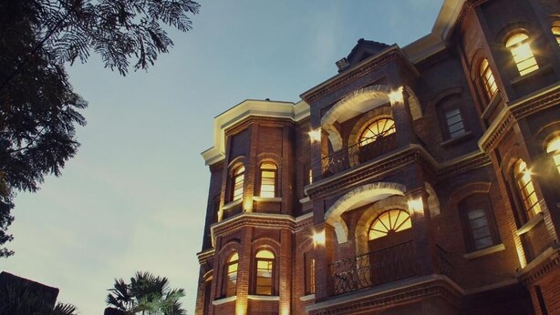 A multi-story building with arched windows and brickwork, featuring balconies and a prominent corner tower. - Jacatra Homestay (Malang)