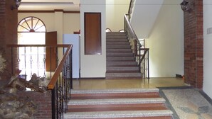 A staircase with wooden railings and a patterned carpet leading to an upper floor. - Jacatra Homestay (Malang)