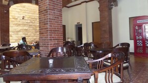 A restaurant with brick pillars, wooden tables, and chairs. - Jacatra Homestay (Malang)