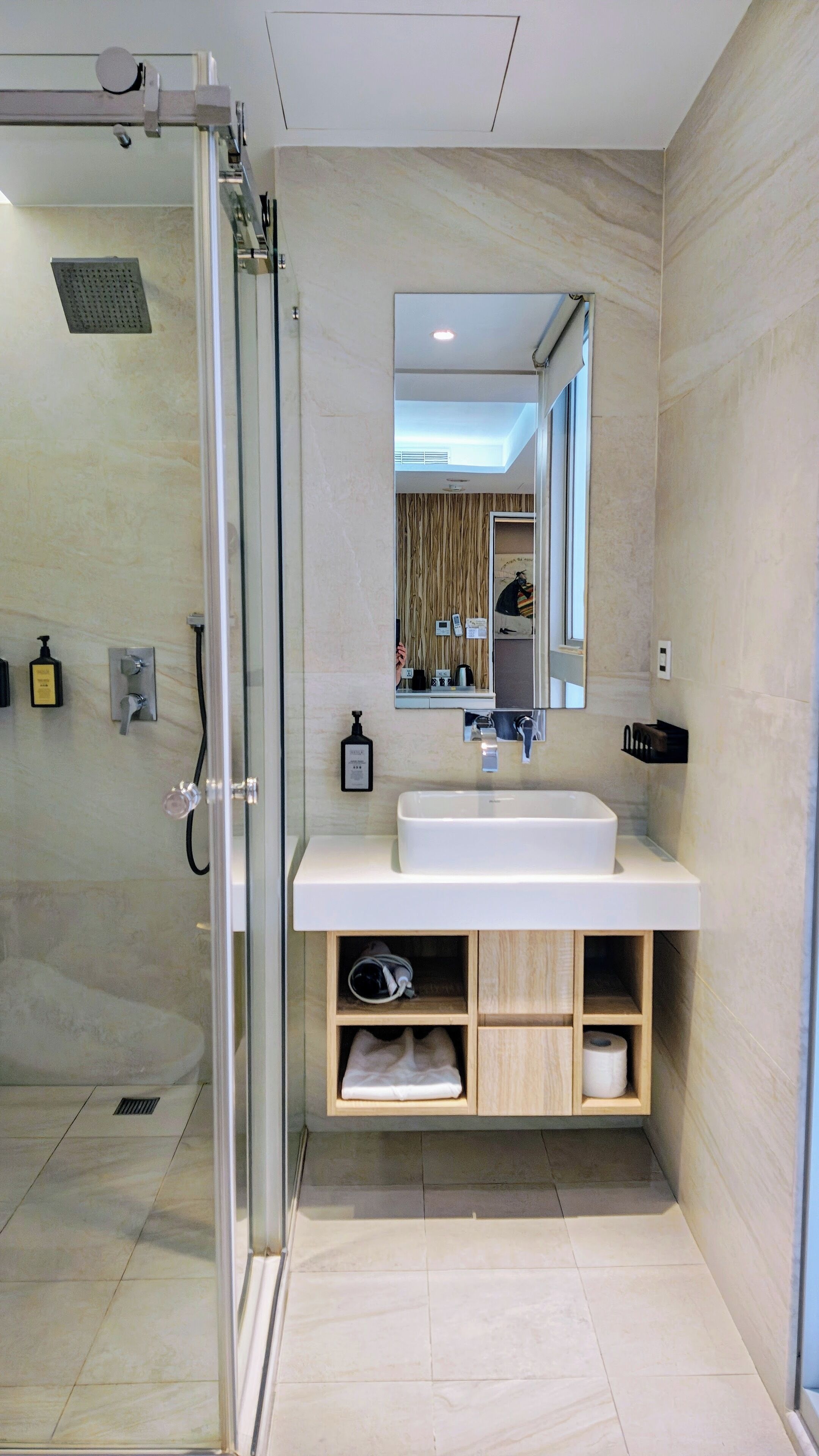 A modern bathroom with a glass shower enclosure, a white sink, and a mirror above it.