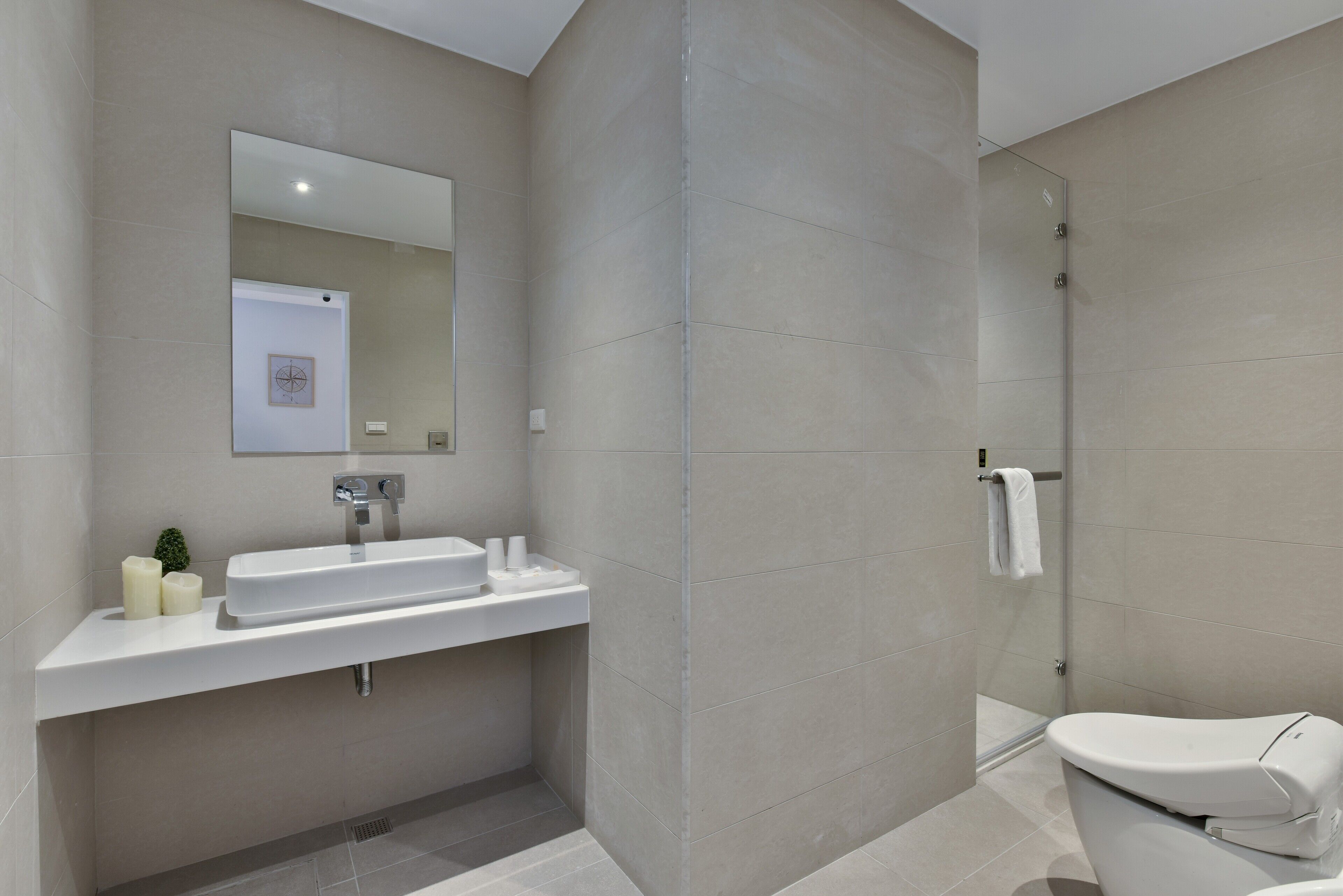 Un baño moderno con lavamanos, espejo y retrete.