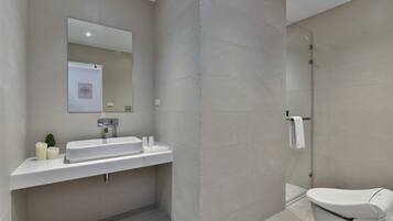 Un baño moderno con lavamanos, espejo y retrete.