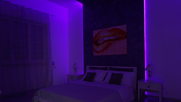 A bedroom with a bed, nightstands, a wall-mounted painting, and a window with curtains. - Mattandrè (Monteroni di Lecce)
