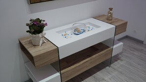 A modern, minimalist desk with a glass top, wooden drawers, and a small potted plant. - Mattandrè (Monteroni di Lecce)