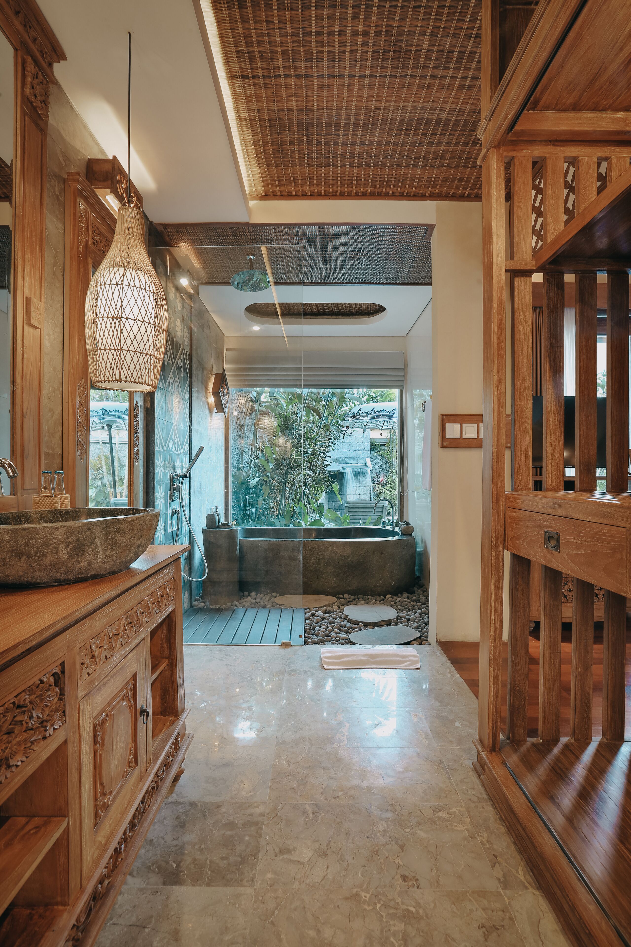 A modern bathroom with a large wooden vanity, a freestanding bathtub, and a view of the outdoors.