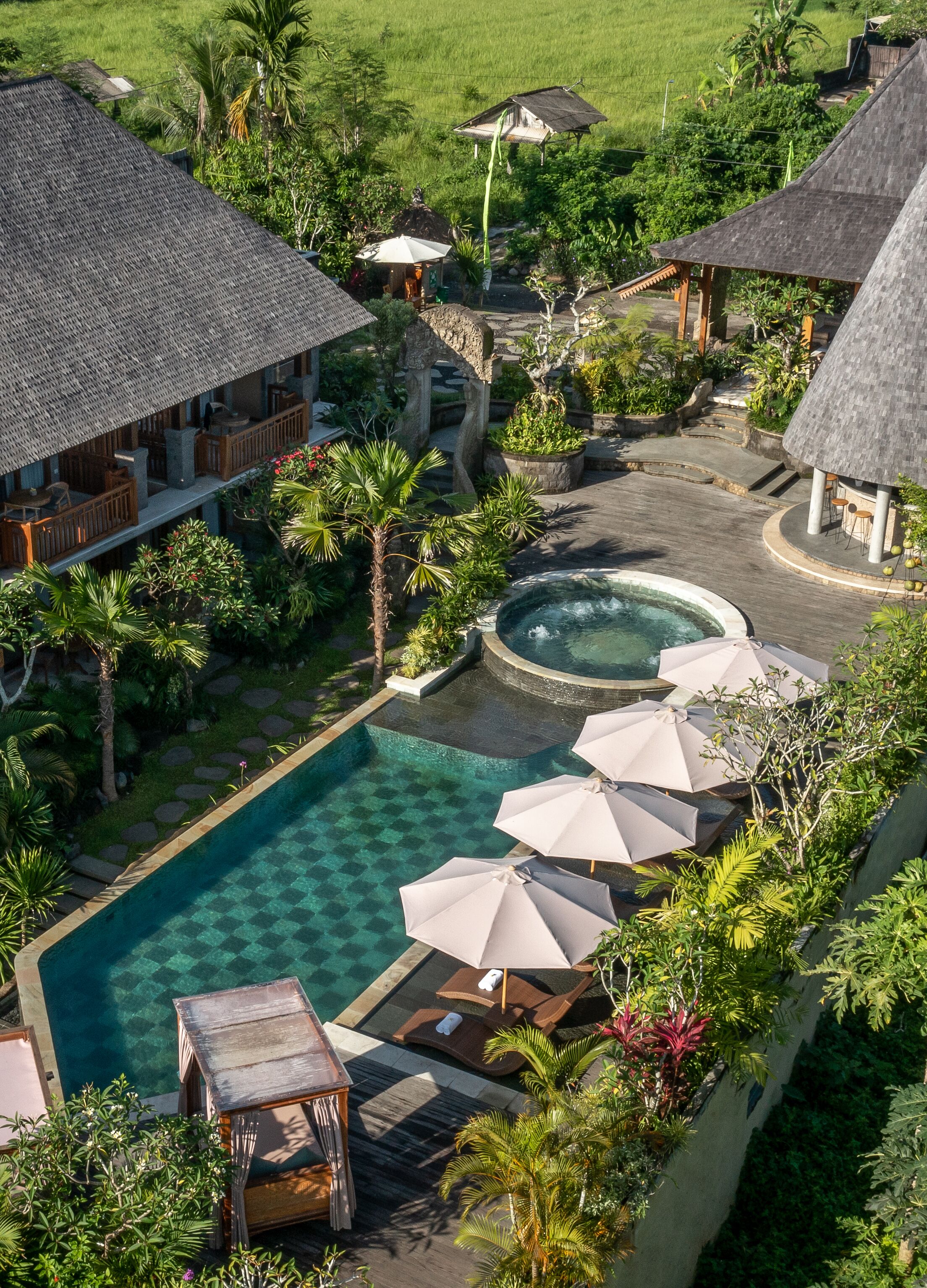 A resort with a swimming pool, lounge chairs, and thatched-roof structures.