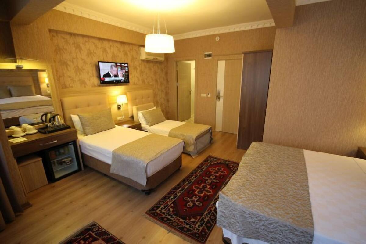 A hotel room with two beds, a TV, a desk with a lamp, and a wardrobe.