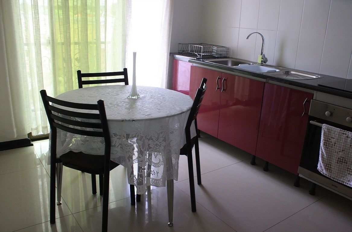 A kitchen with a round table, chairs, a sink, and cabinets.