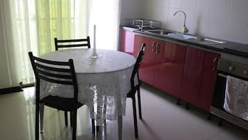 A kitchen with a round table, chairs, a sink, and cabinets.