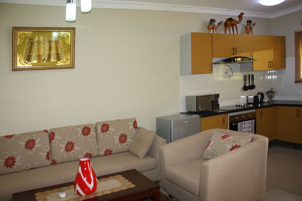 Una sala de estar con un sofá, una mesa de centro y una cocina con armarios y electrodomésticos.