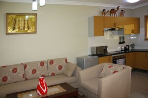 Una sala de estar con un sofá, una mesa de centro y una cocina con armarios y electrodomésticos.