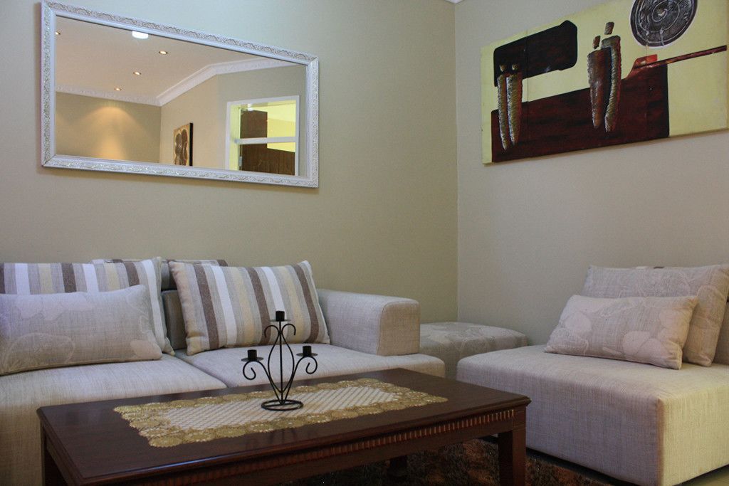 A living room with two sofas, a coffee table, a mirror, and a painting on the wall.