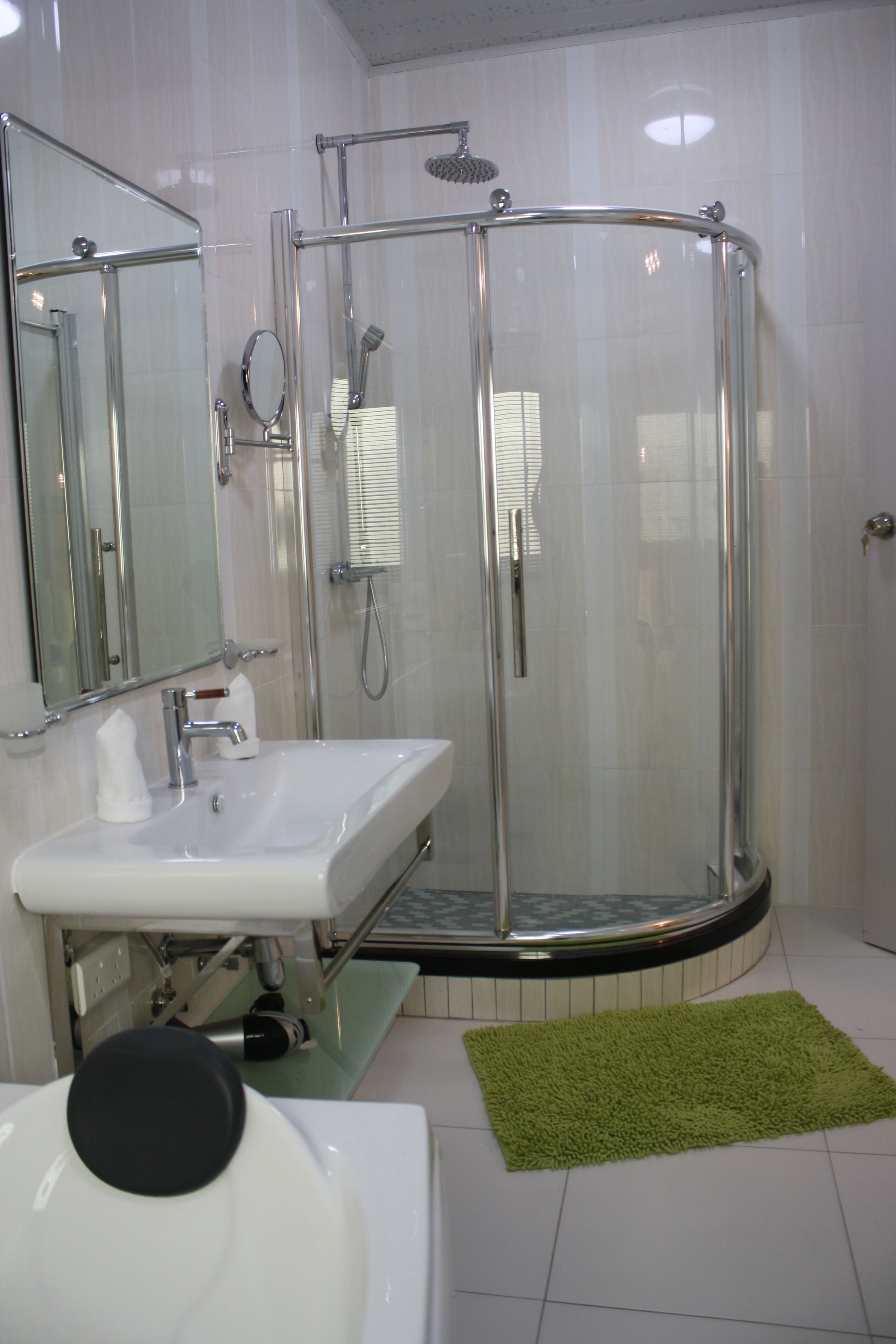 A modern bathroom with a glass-enclosed shower, a white sink, and a mirror.
