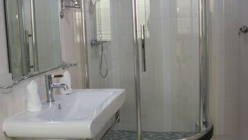 Un baño moderno con ducha de vidrio, lavamanos blanco y espejo.