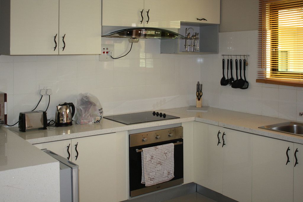 A kitchen with white cabinets, a stainless steel oven, a gas stove, and a window with blinds.