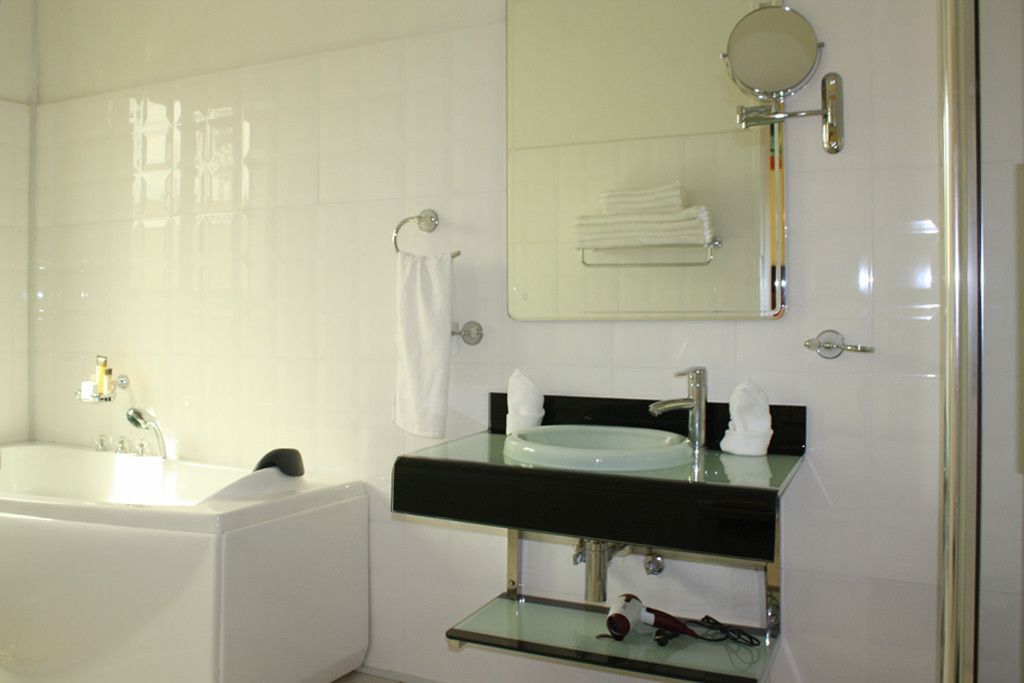 A modern bathroom with a glass-enclosed sink, a large mirror, and a bathtub.