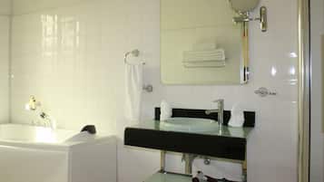 A modern bathroom with a glass-enclosed sink, a large mirror, and a bathtub.