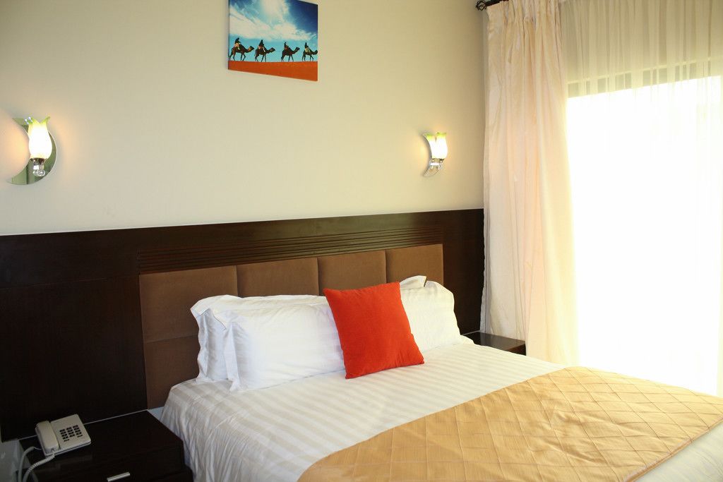 A hotel room with a bed, a nightstand, a telephone, and a painting on the wall.