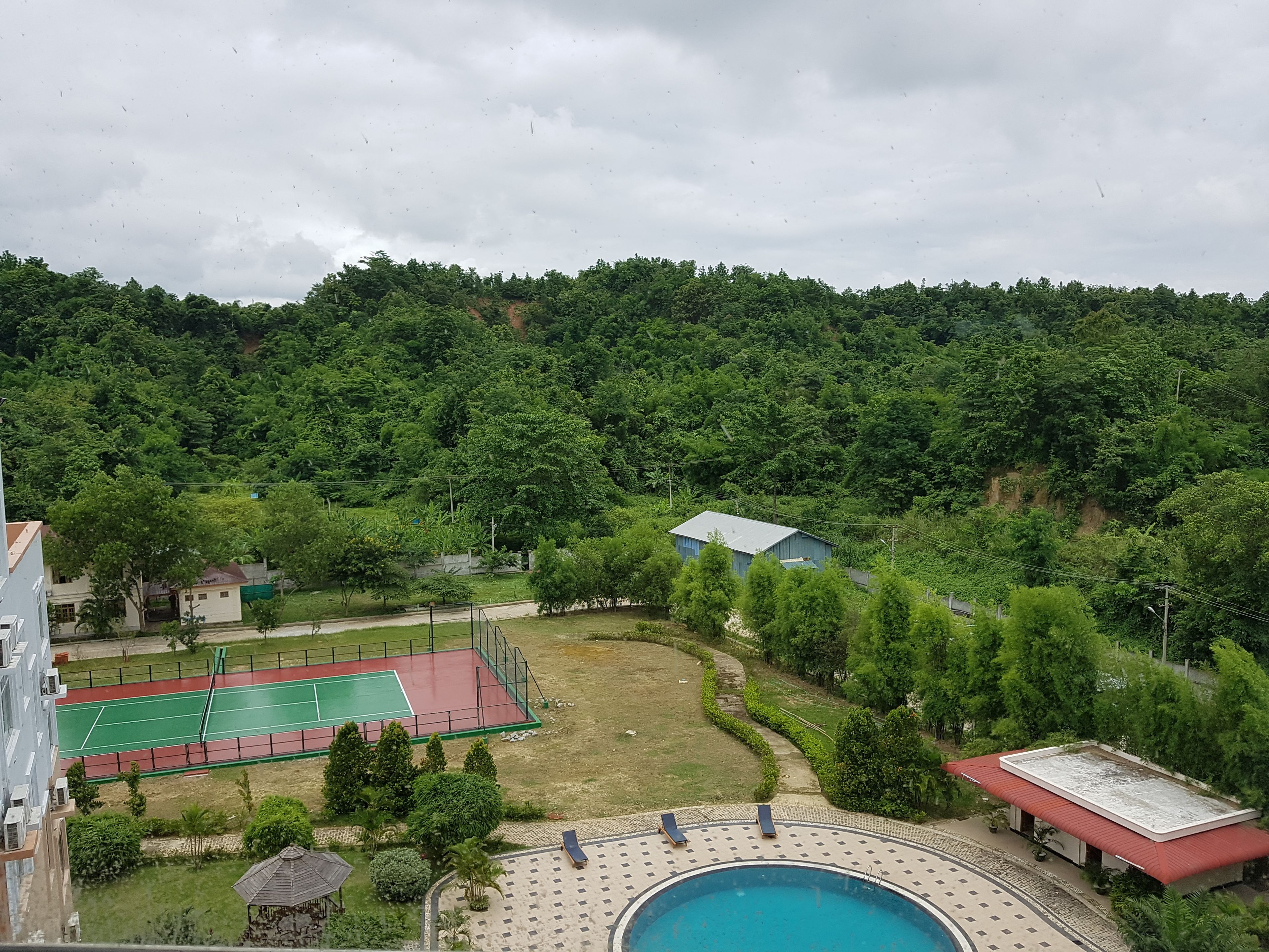 A residential area with a swimming pool, tennis court, and lush greenery.