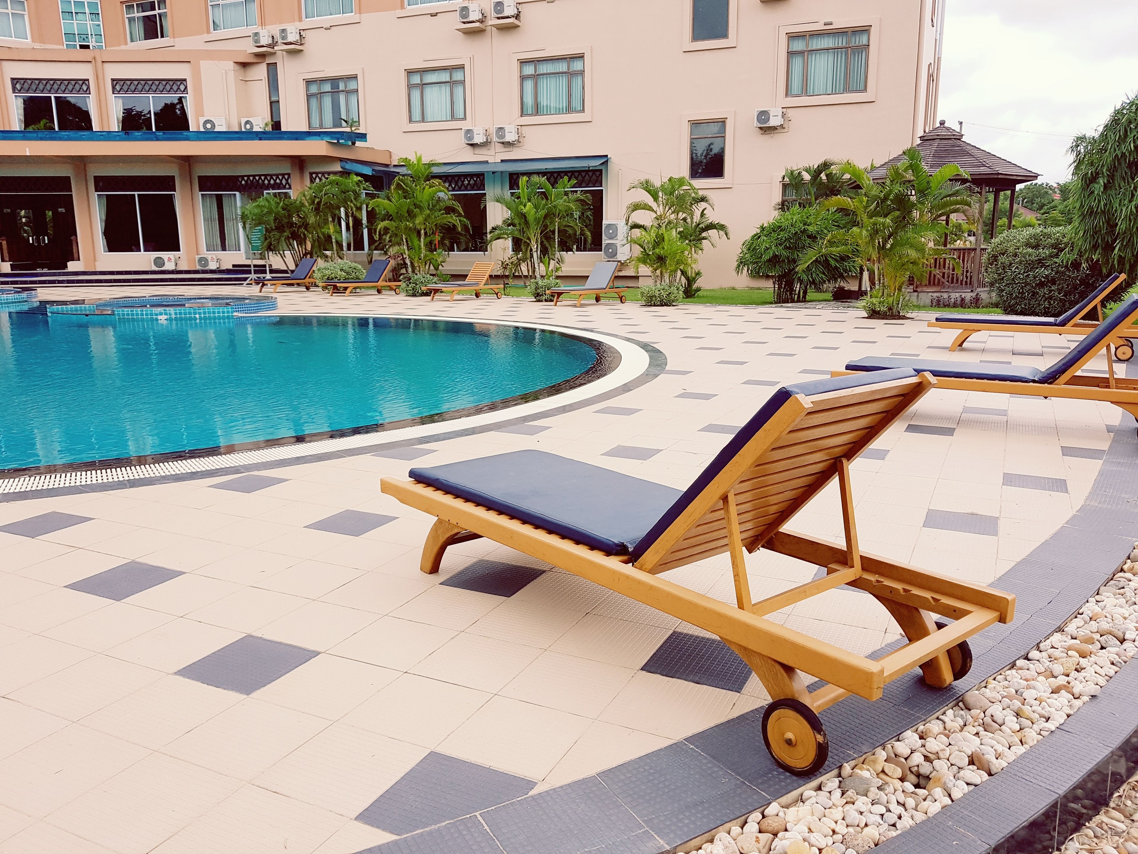 A pool area with lounge chairs and a building in the background.