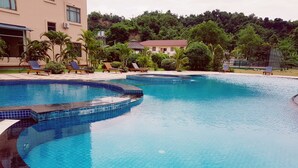 A swimming pool with a tiled edge, lounge chairs, and a building in the background. - Oattara Thiri Hotel (Oattara Thiri Township)