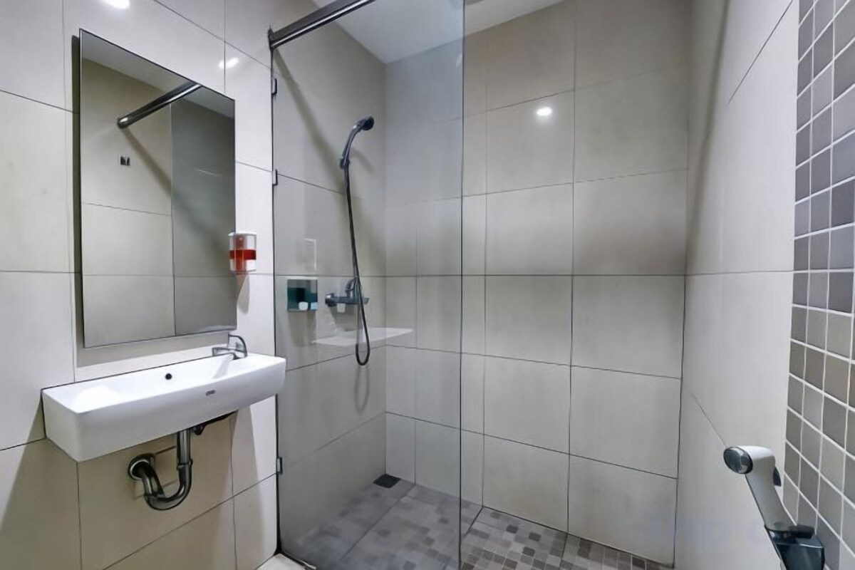 A bathroom with a white sink, mirror, and shower.