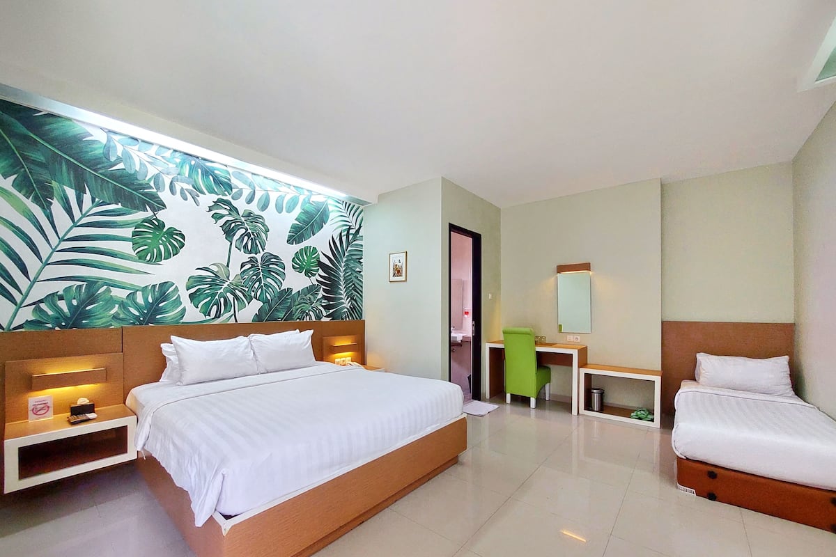 Quarto de hotel com uma cama grande, uma mesa, uma cadeira e um banheiro visível por uma porta aberta.