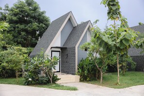 A modern house with a grey roof and white trim, surrounded by lush greenery and a well-maintained lawn. - Sabai Hotel Lopburi (Tha Wung)