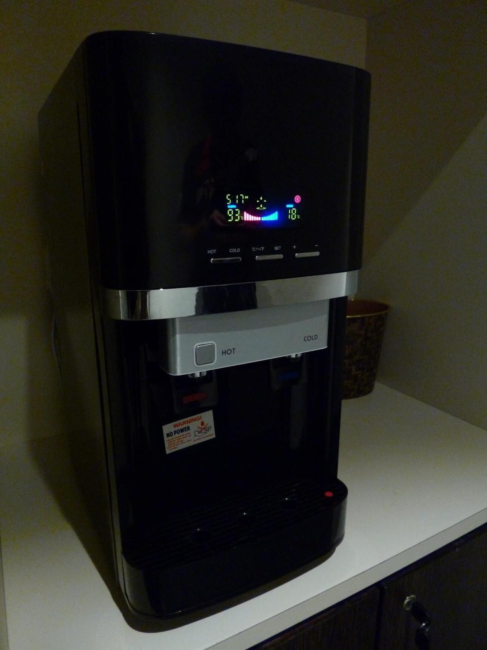 A black coffee maker with a digital display on a white countertop.