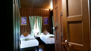 Een hotelkamer met twee bedden, houten lambrisering en twee ingekaderde foto's aan de muur.