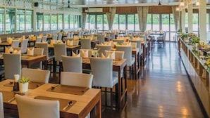 A spacious restaurant with multiple tables and chairs, large windows, and a wooden floor. - Baan Amphawa Resort & Spa (Amphawa)
