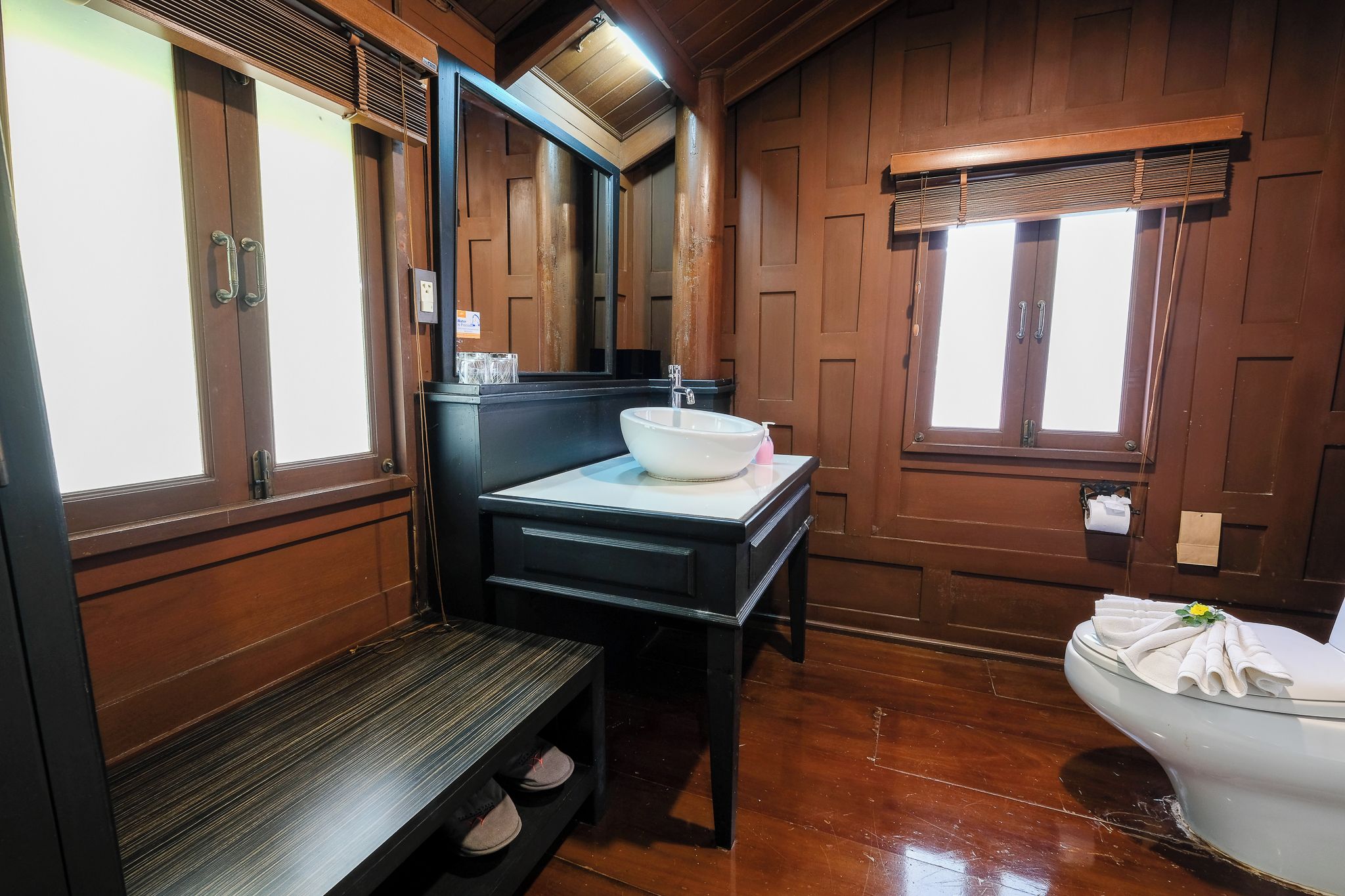 A bathroom with a wooden vanity, a sink, a mirror, and a toilet.