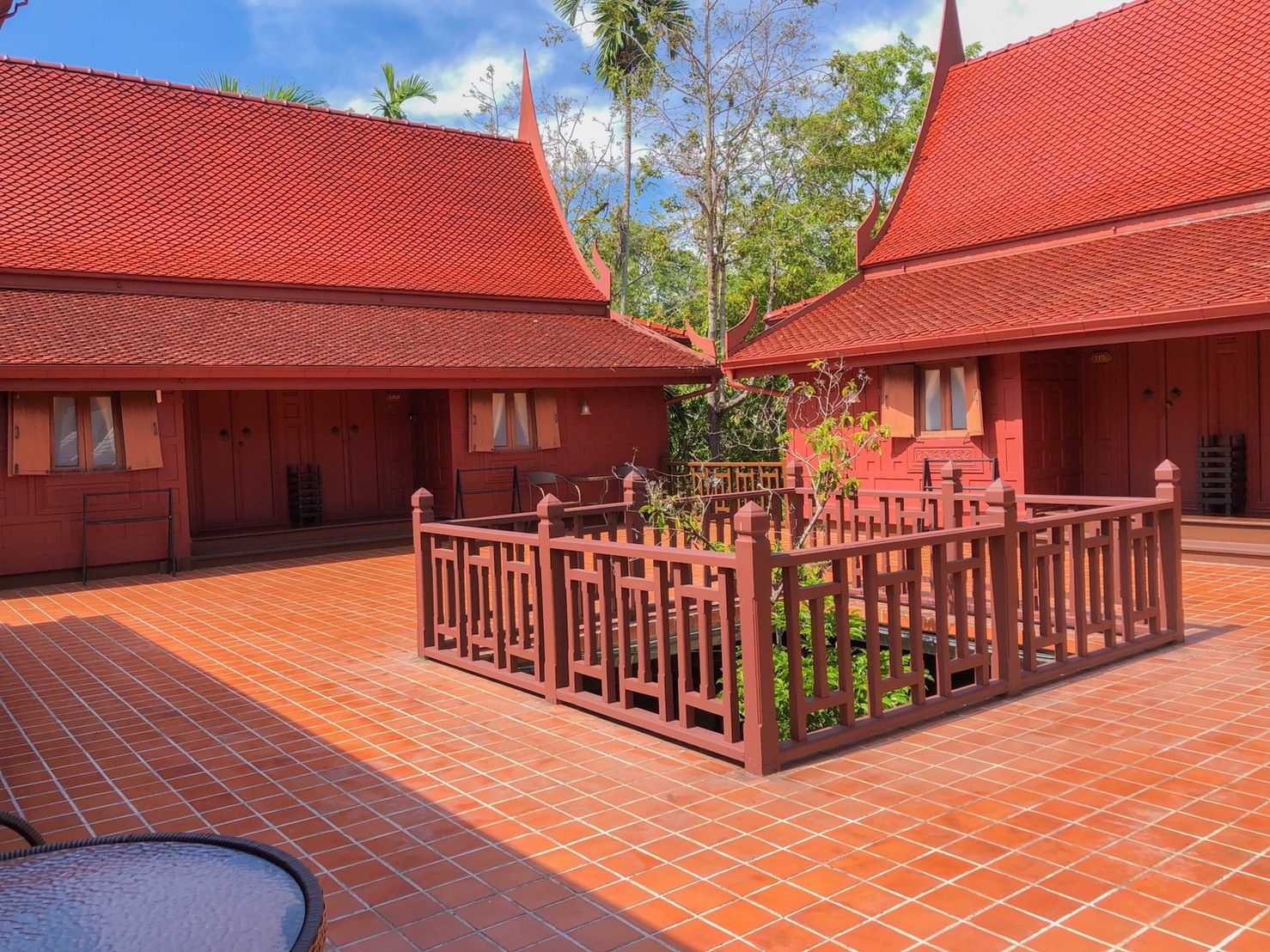 Un patio con edificios de techo rojo, un jardín central y piso de baldosas.