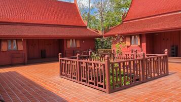 Un patio con edificios de techo rojo, un jardín central y piso de baldosas.